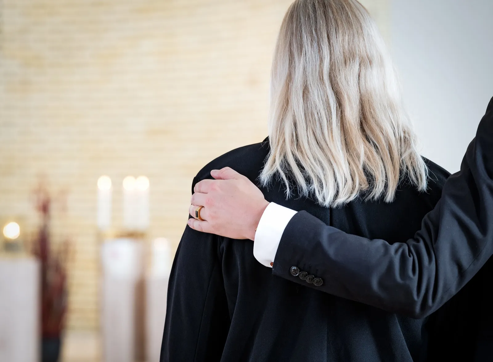 Eine Hand liegt tröstend auf der Schulter einer trauernden Frau